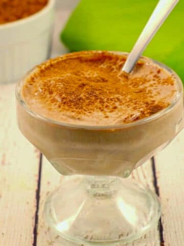 Chocolate Greek yogurt in a glass dessert dish with a spoon.