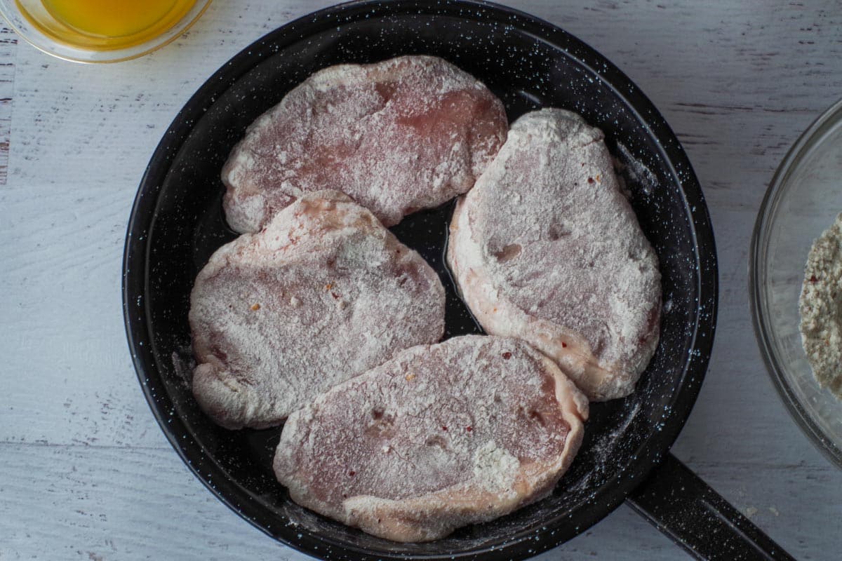 4 pieces of flour coated pork in skillet.