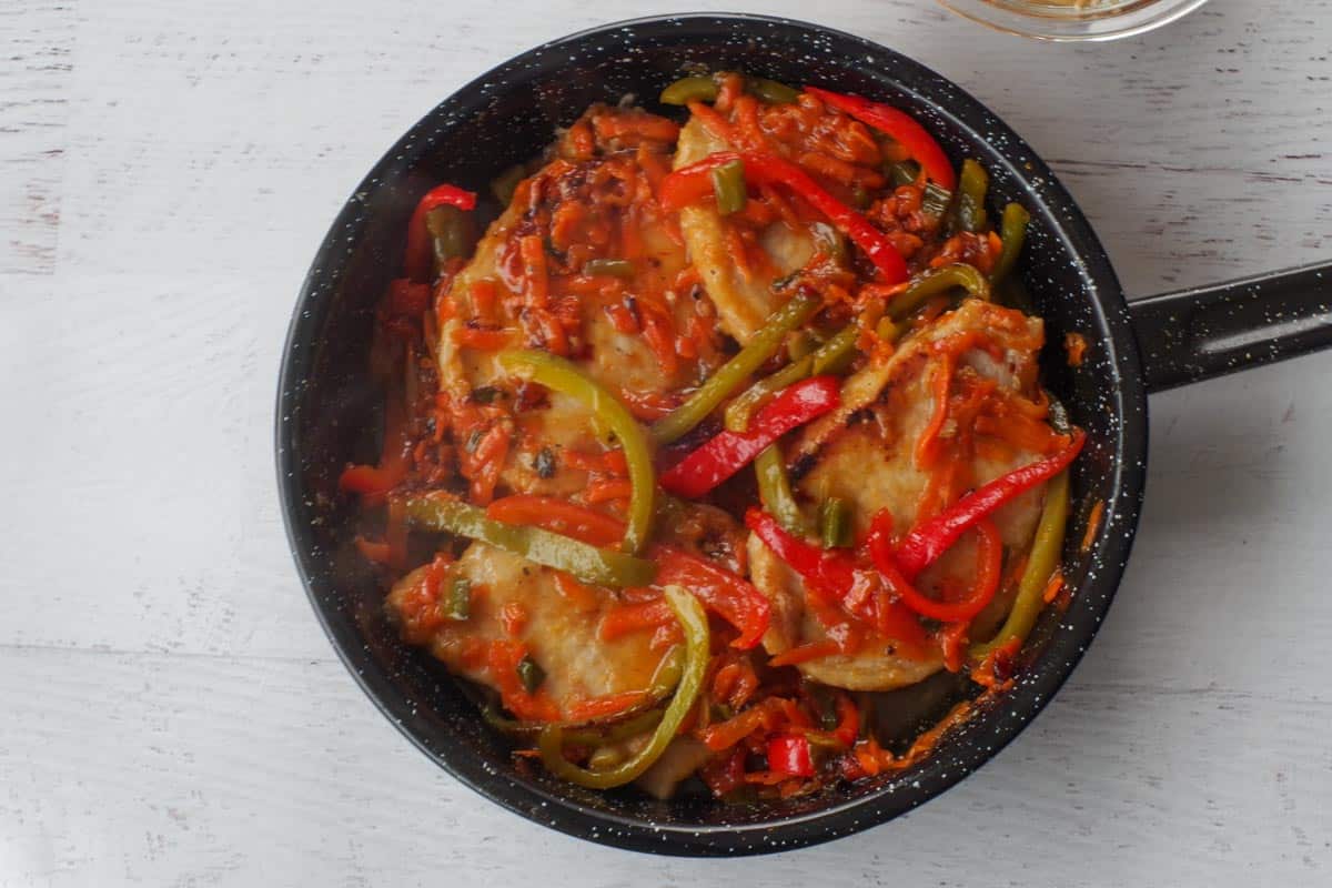 Cooked pork with vegetables in pan. 