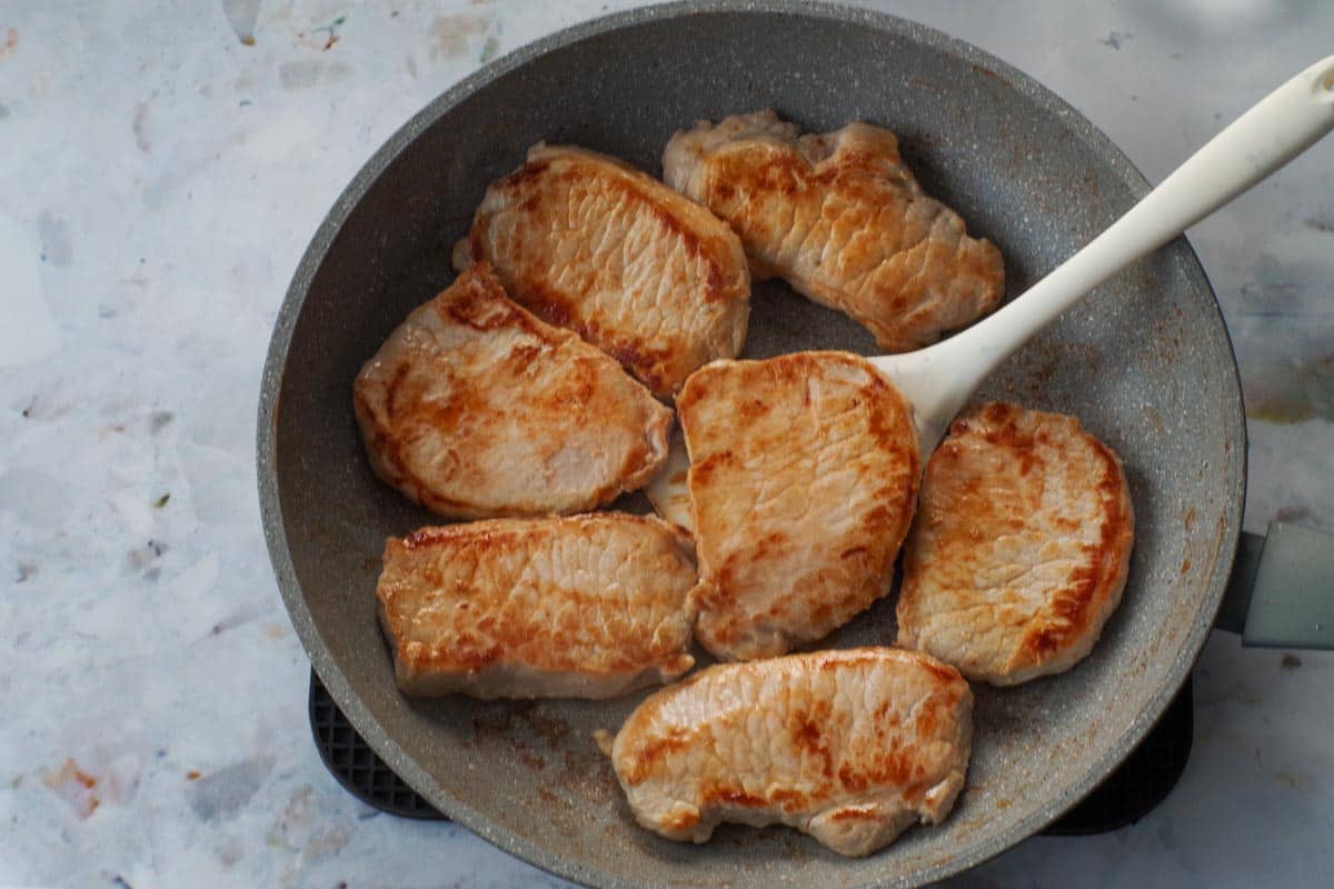 Pork browned on each side, in a frying pan.
