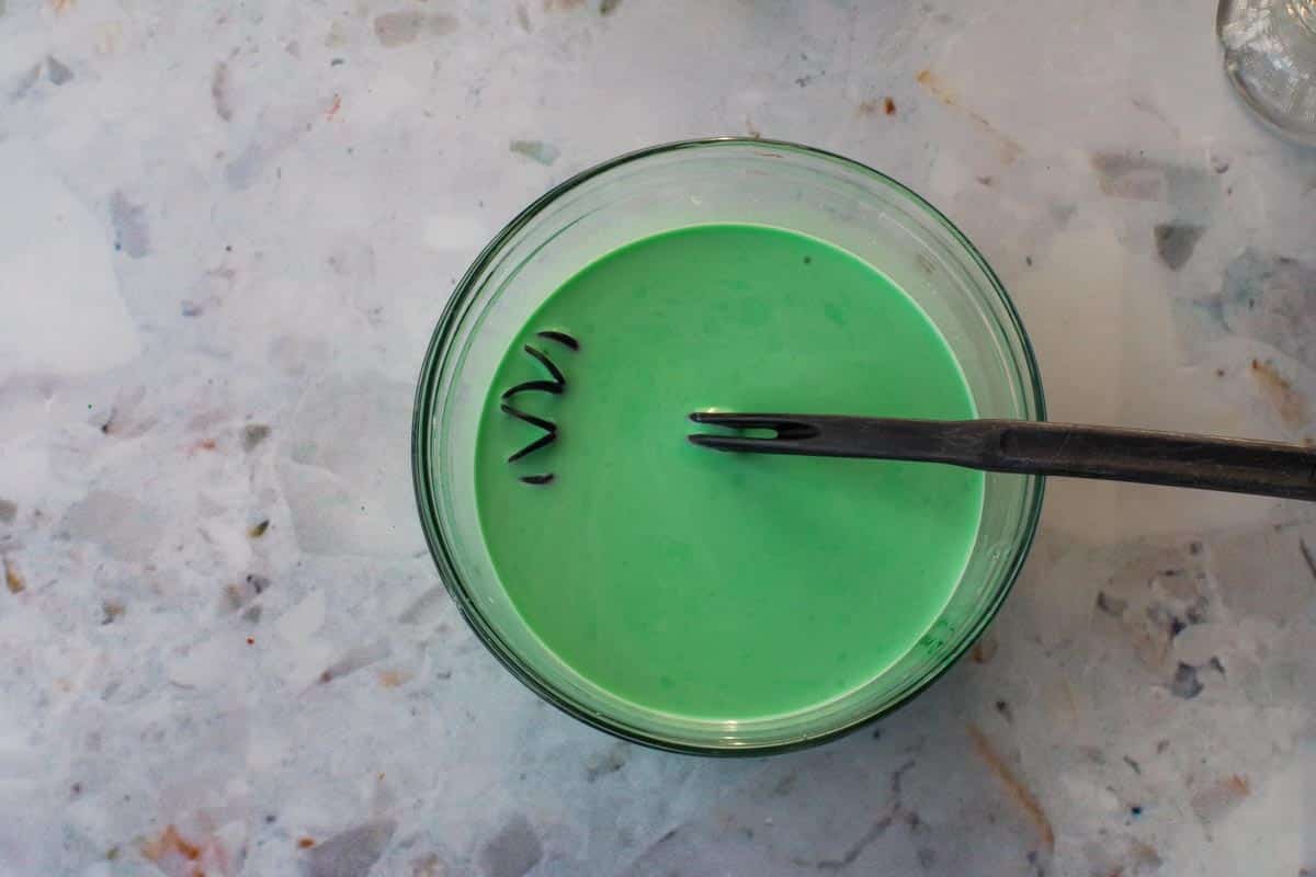 Green food coloring added to bowl with hot chocolate mixture.