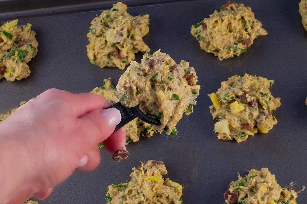 Cookie dough being dropped by the heaping tablespoonful onto cookie sheet.