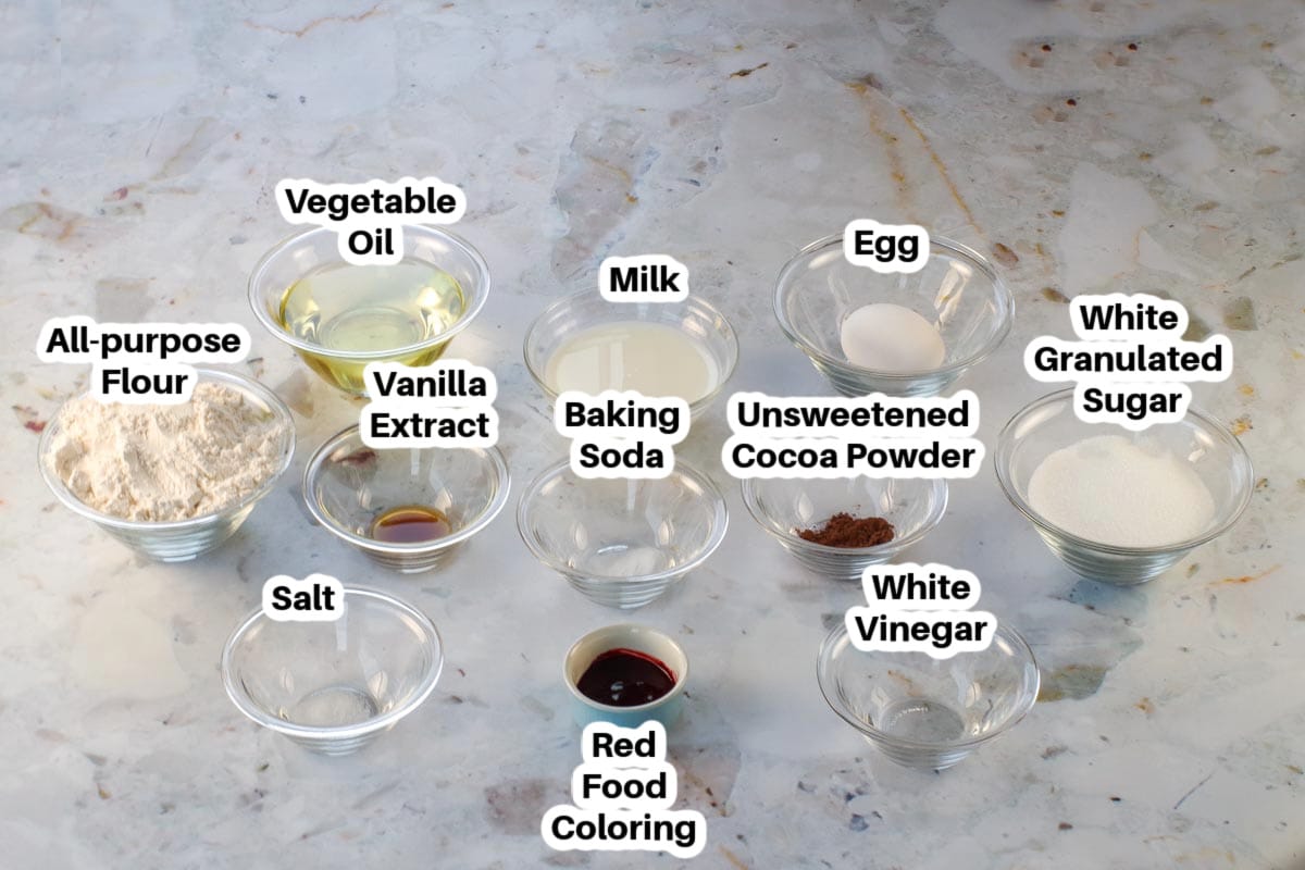 Ingredients needed for red velvet cake in glass bowls, labelled.