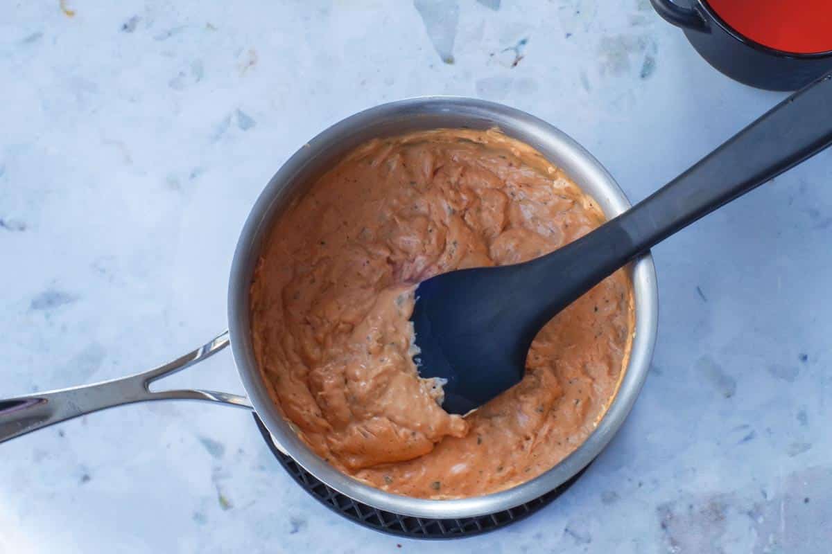 ww buffalo chicken dip ingredients melted together in a pot with a black spatula
