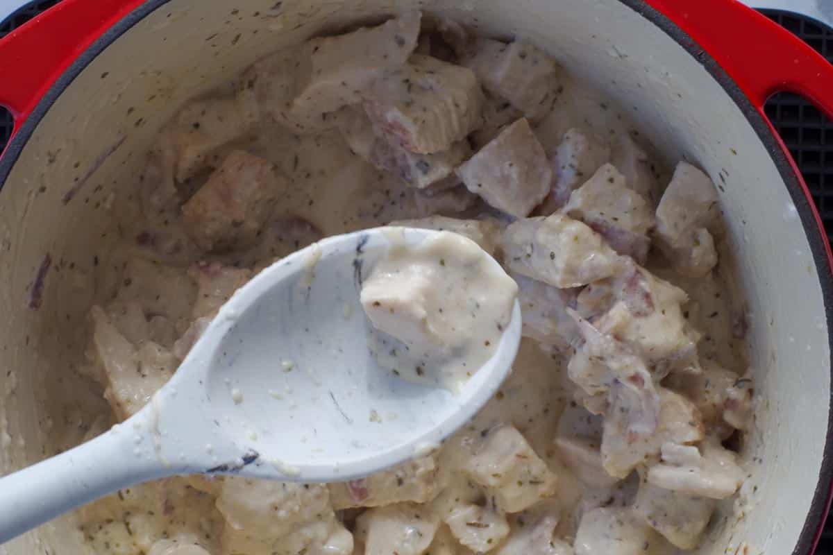 Consistency of sauce beig held up on a spoon over pot.