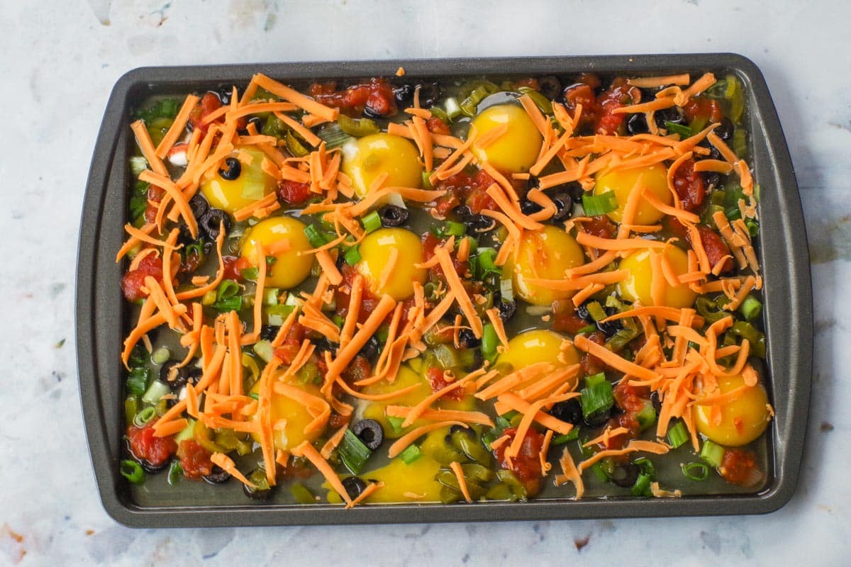 Cheese added to sheet pan with eggs and toppings.