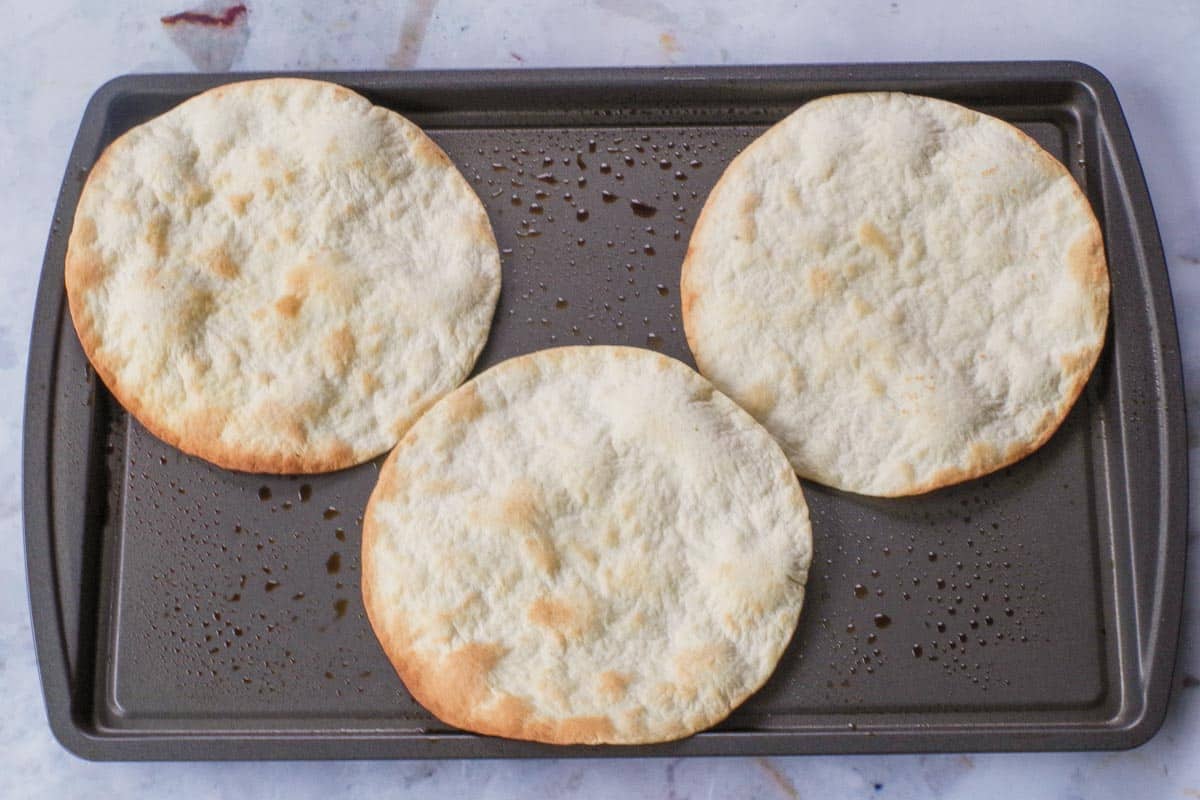 Baked tortillas on a sheet pan, removed from the oven.