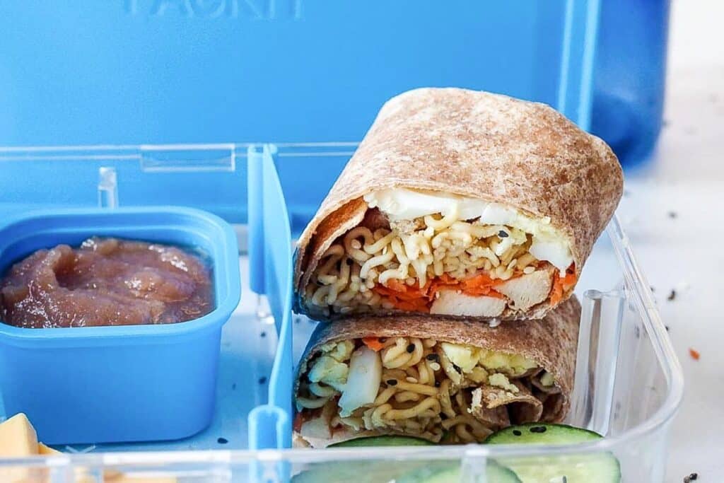 Ramen wrap stacked in a bento lunchbox beside a berry sauce