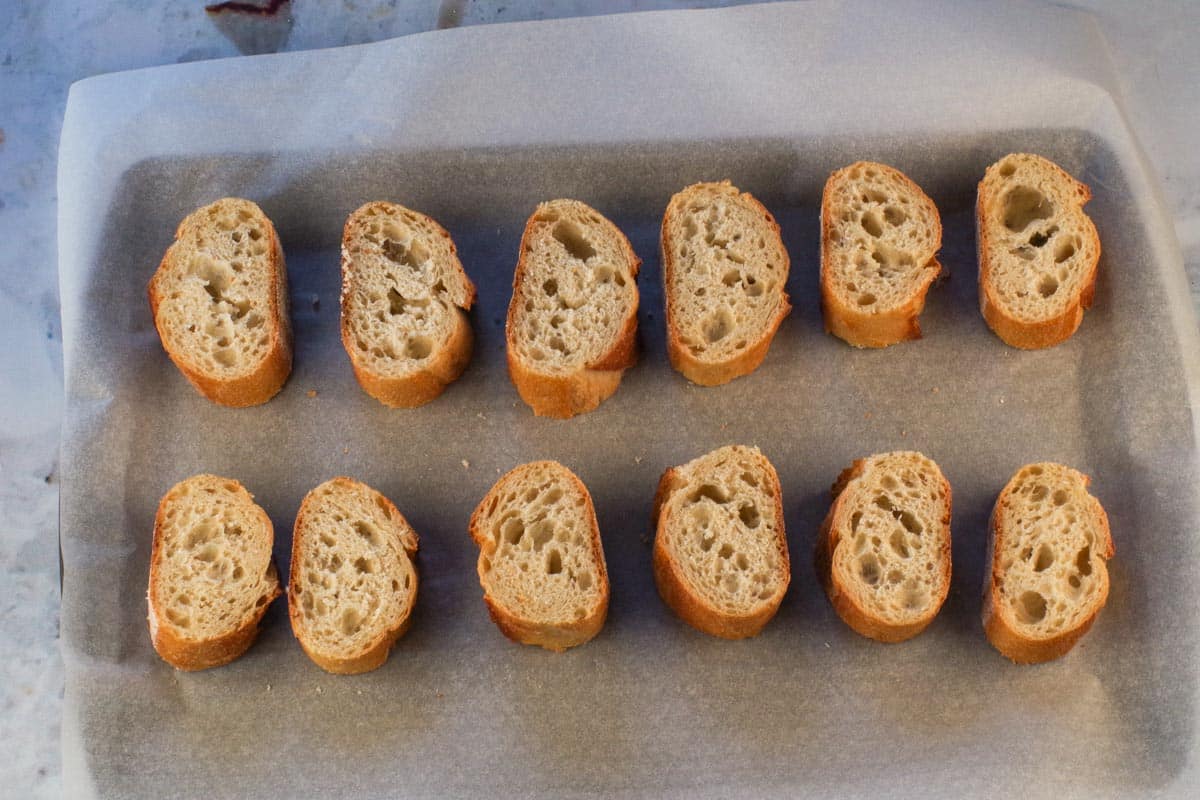 Baguette pieces on parchment-lined baking sheet.