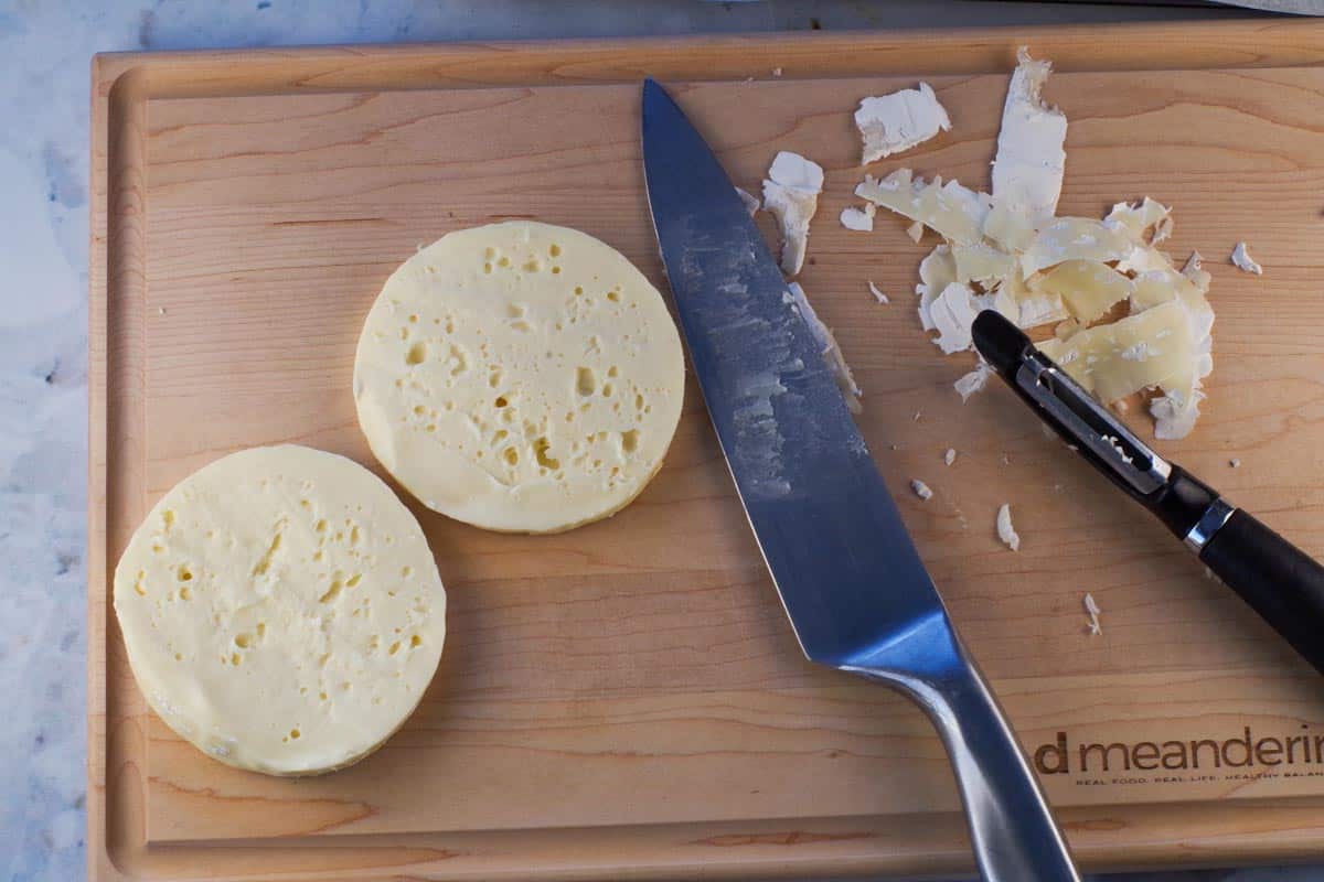 Brie peel around edges and cut in half on a cutting board with a knife.