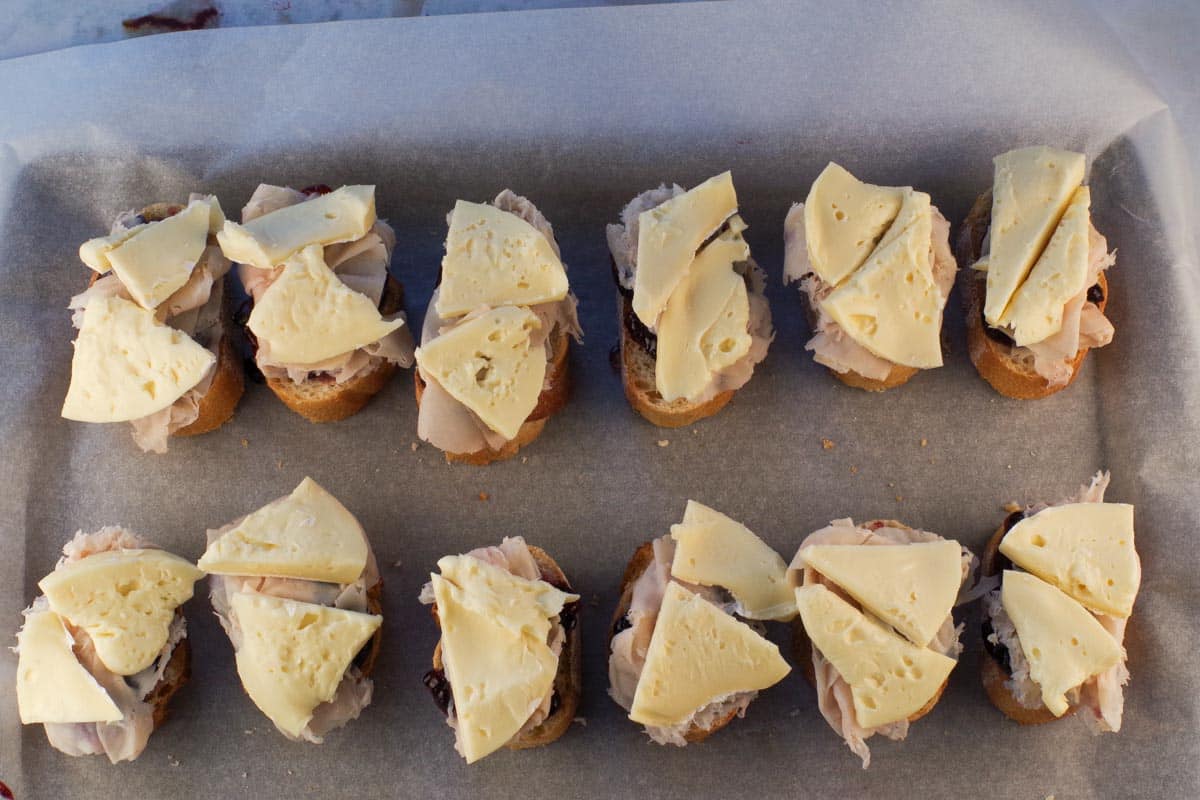 Brie slices on baguettes on parchment-lined baking sheet.