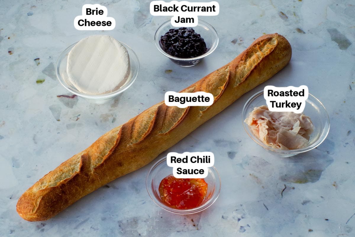 Ingredients in Turkey Brie Bites in glass bowls labelled, with a baguette in the middle.