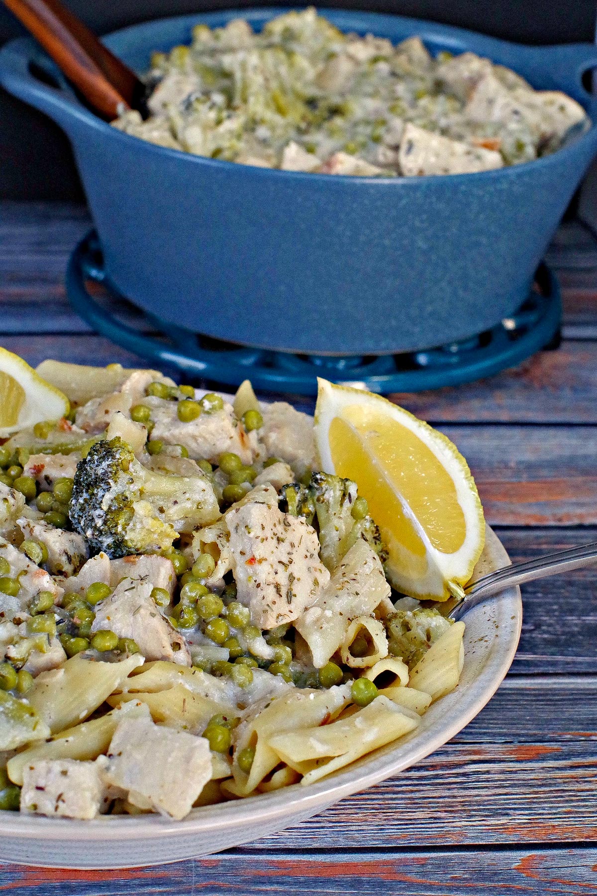 A bowl of Weight Watchers Lemon Chicken Pasta, with more in a blue pot in the background.