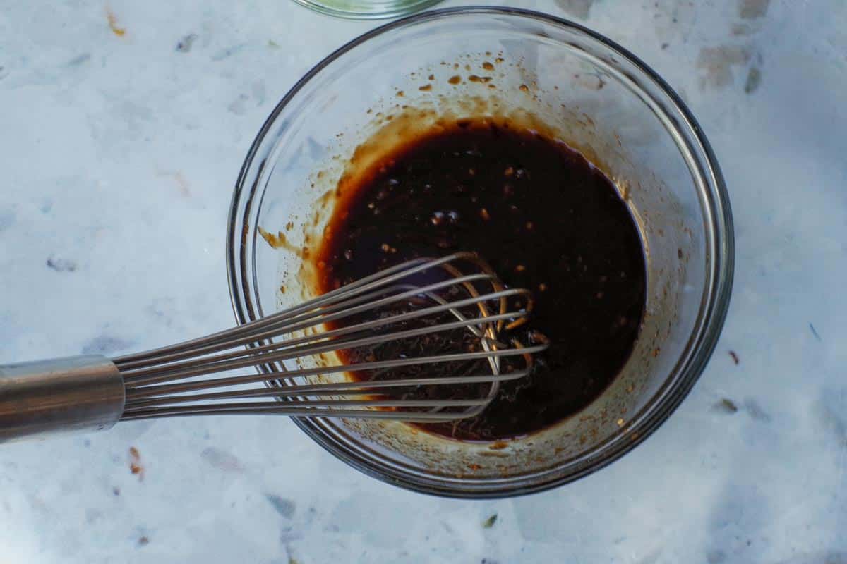 Sauce mixed together in glass bowl with metal whisk.