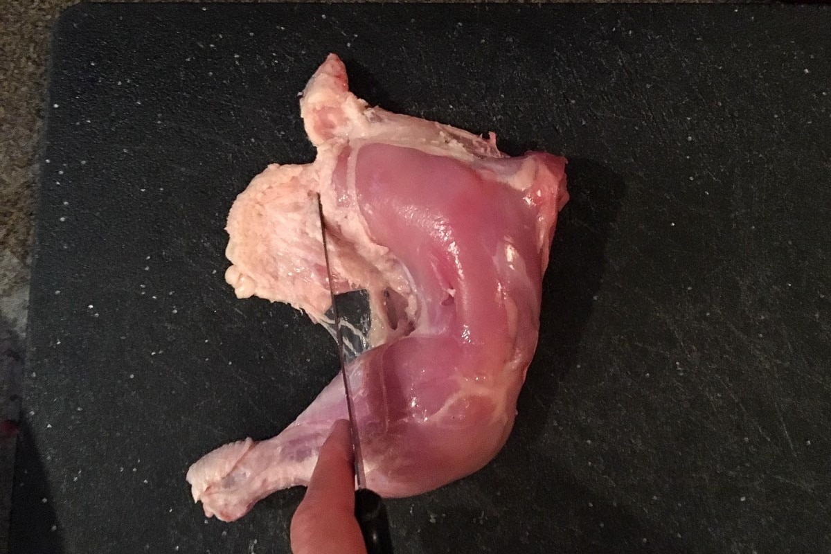Excess skin being trimmed off piece of chicken.
