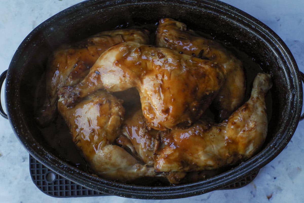 Cooked hoisin chicken quarters in a roasting pan.