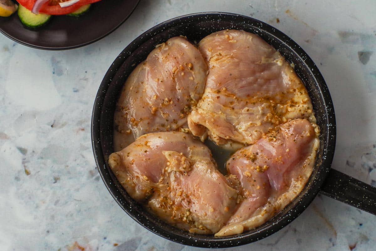 Raw marinated chicken in frying pan.