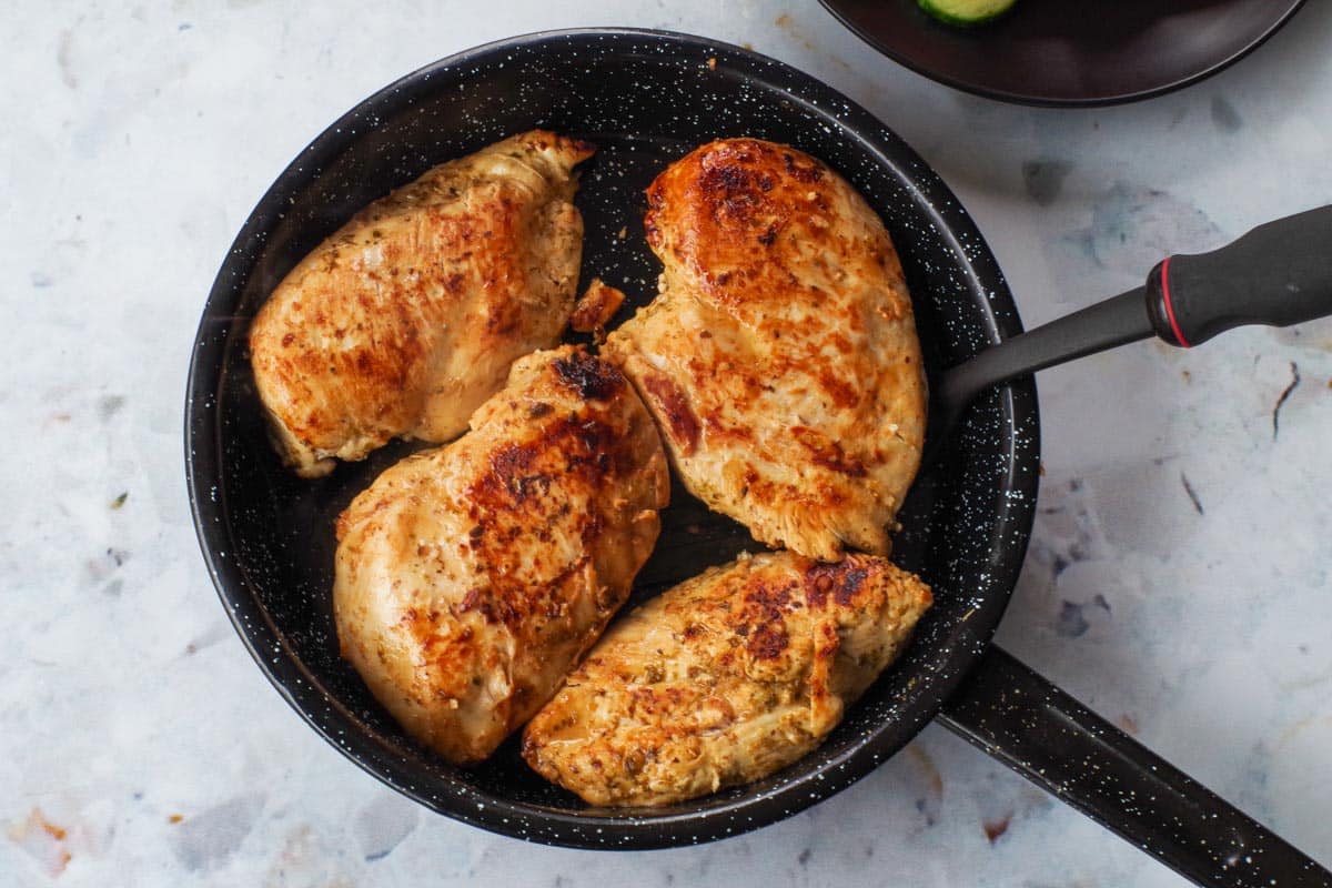 Cooked chicken breast in frying pan.