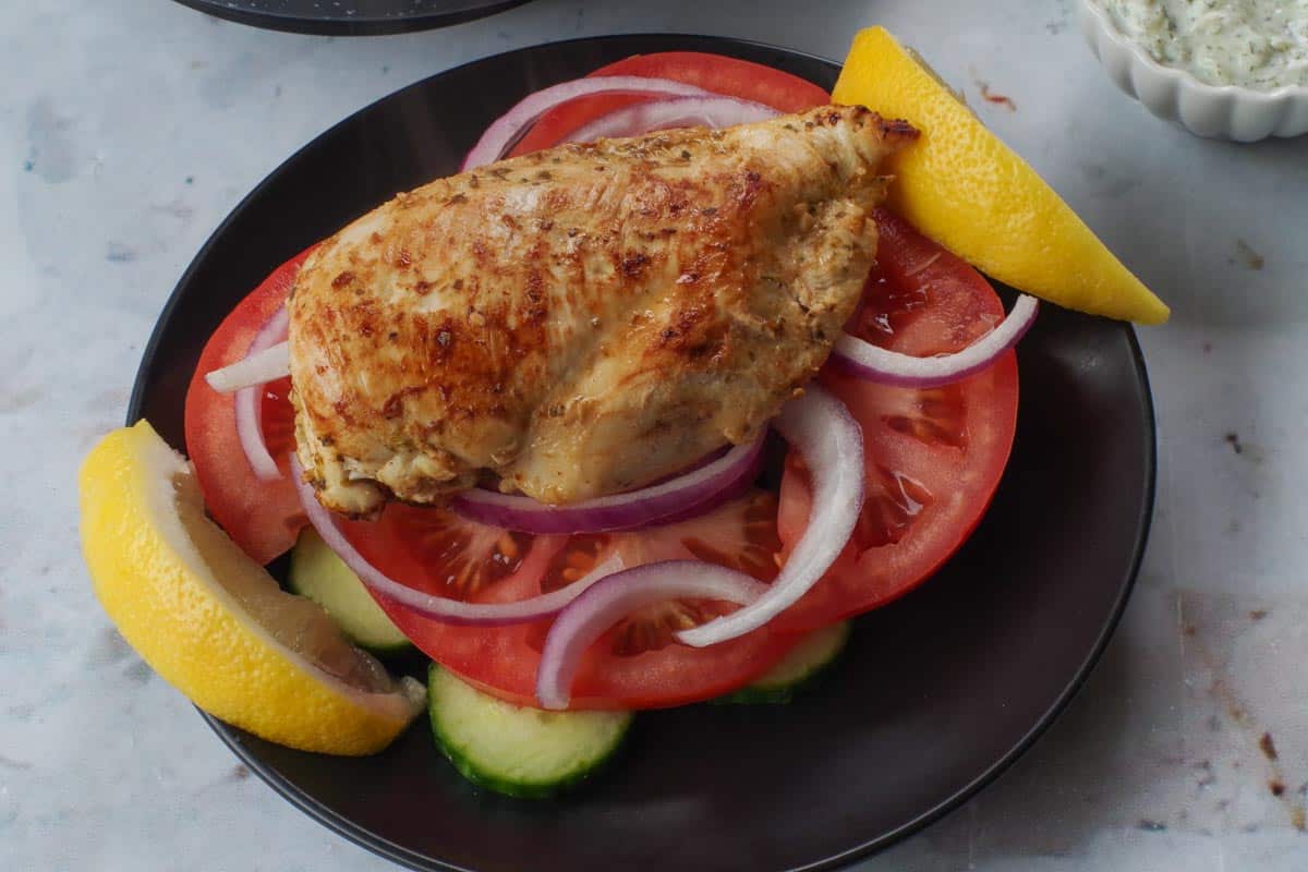 Chicken breast on top of bed of vegetables.
