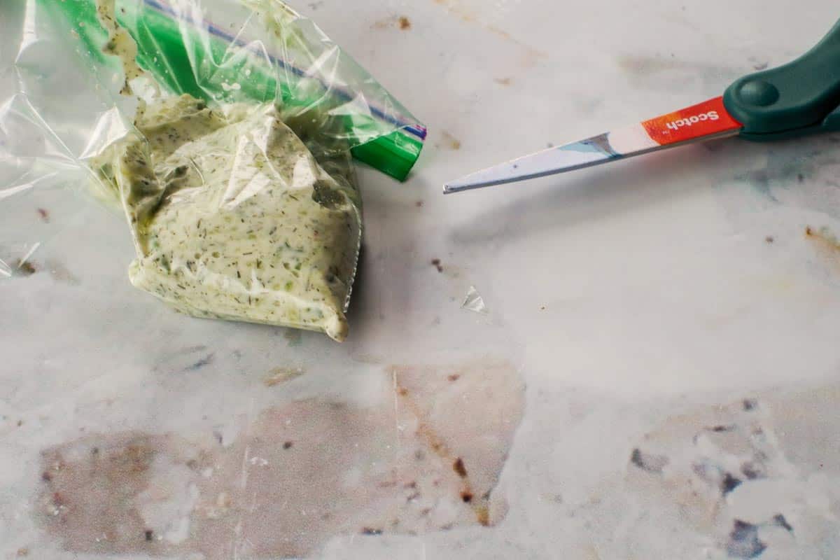 Tzatziki in ziploc bag with tip cut off and scissors beside the bag.