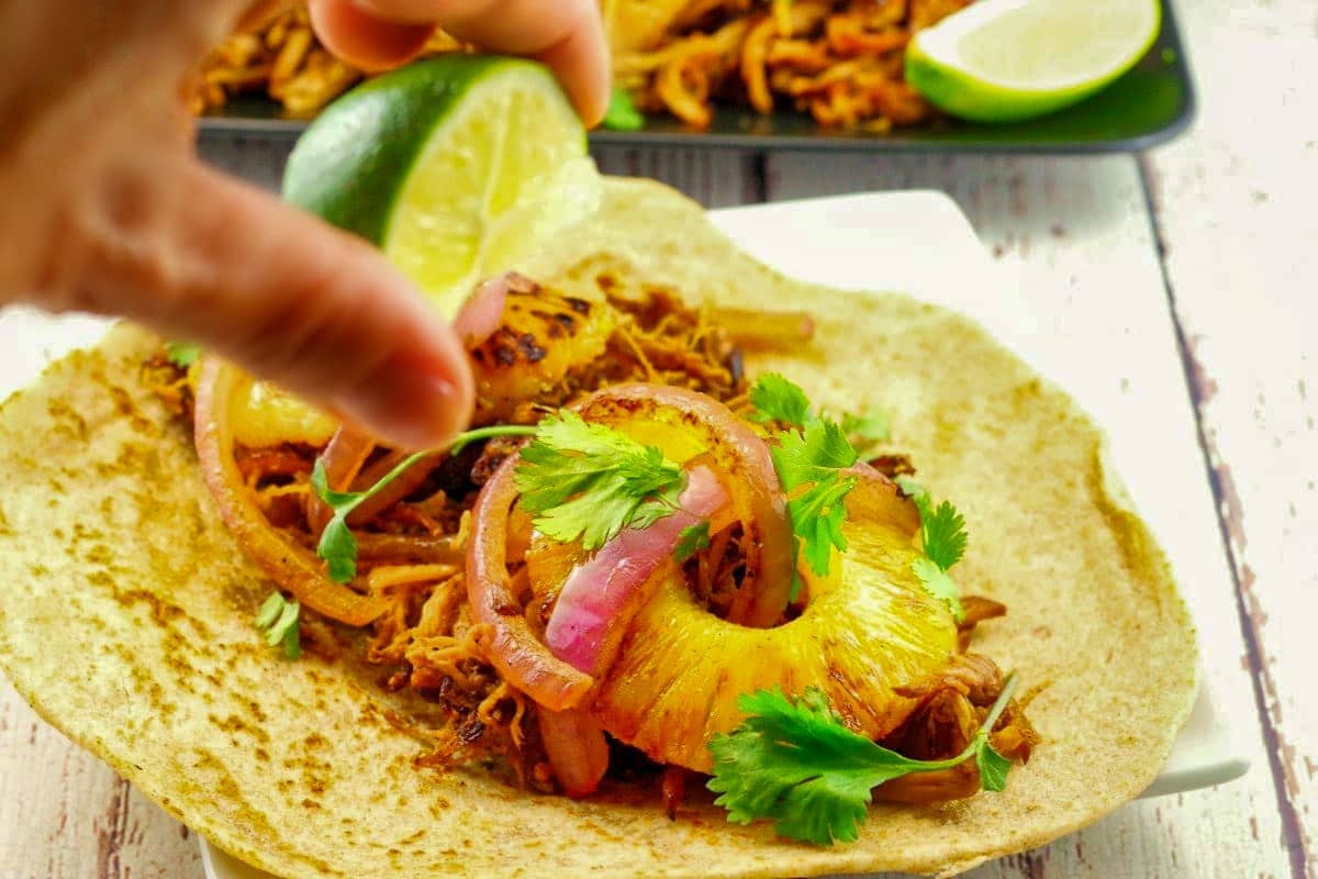 Crock Pot Pineapple Pork Carnita with lime being squeezed over it.