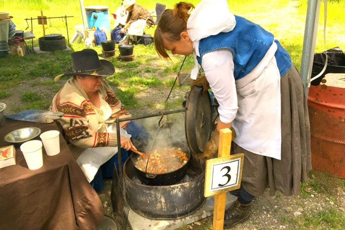 Contestants dressed up in old timey clothes cooking stew for Bar U Ranch Stew Cook-off