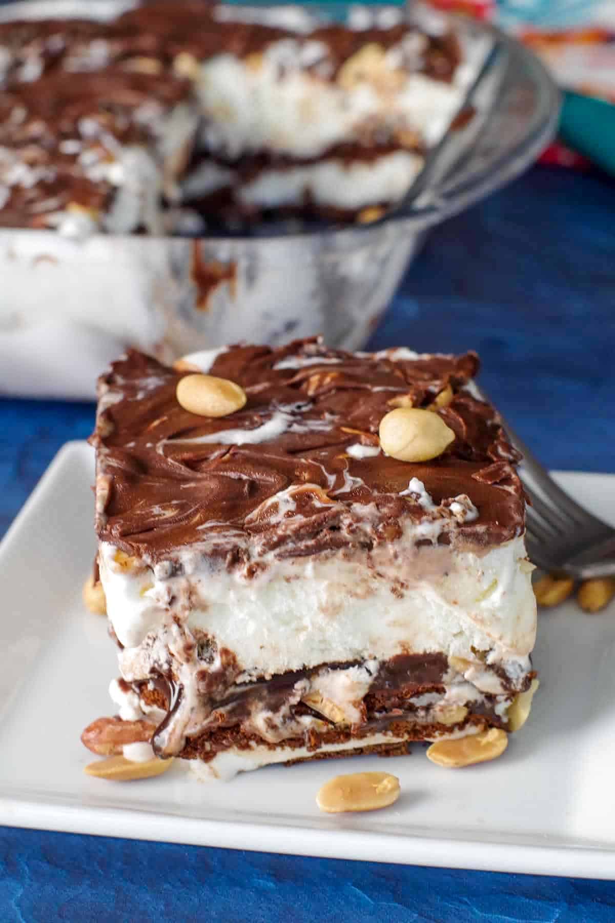 piece of buster bar ice cream cake on white plate with fork and whole glass pan in background