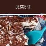 Buster Bar dessert in a pan with a piece missing and a spatula lifting a piece out.