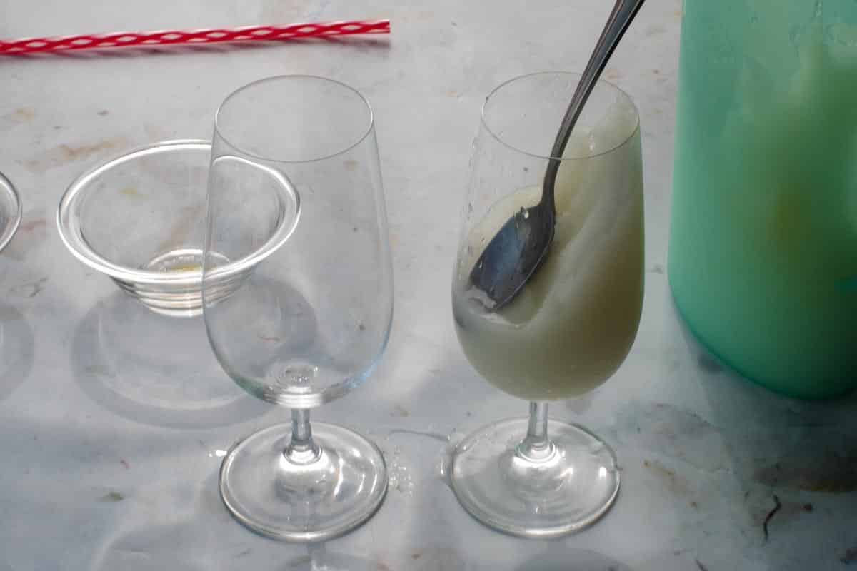 Pina Colada mixture poured into glass and pushed down on an angle with a spoon.