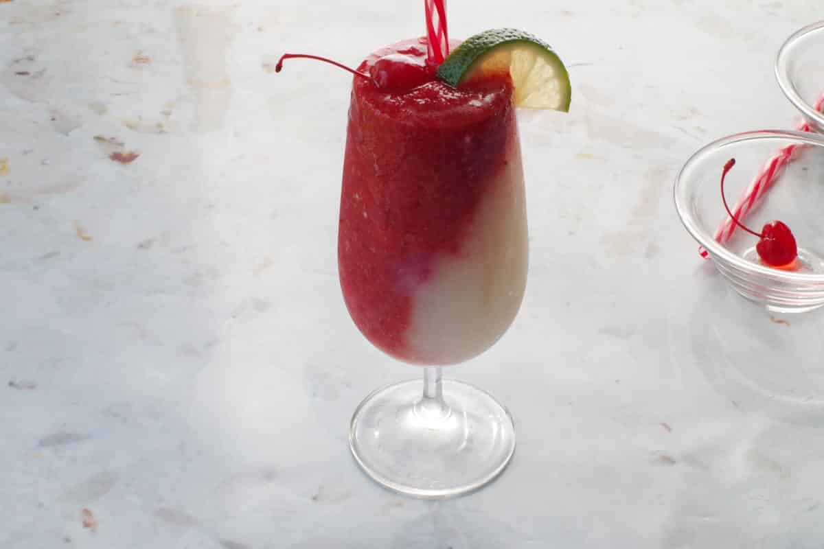 Miami vice garnished with lime wedge and maraschino cherry.