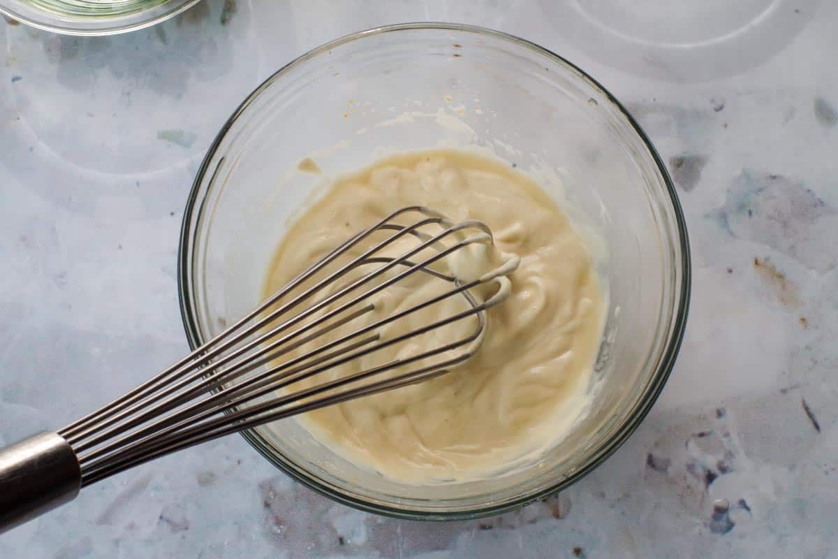 Mayonnaise, sauerkraut liquid and Dijon mustard whisked together in a glass bowl.
