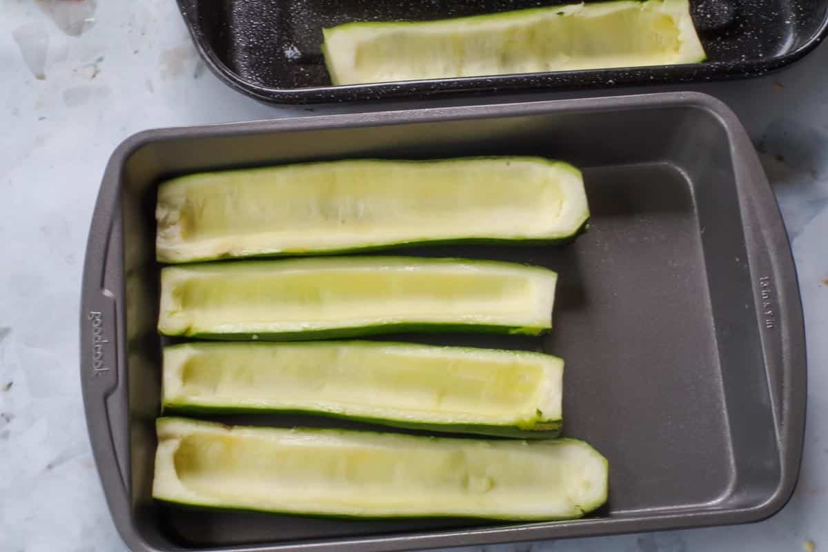 Hollowed out zucchini halves in baking dish.