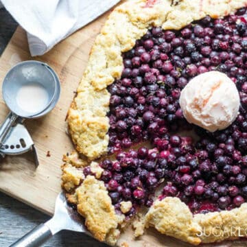 Saskatoon Berry Galette with a scoop of vanilla ice cream on top and an ice cream scoop on the side.