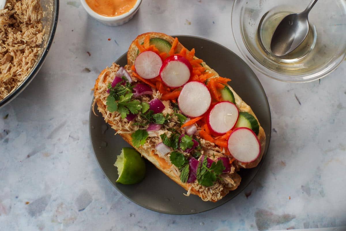 Radishes, cucumber and carrots added to other side of bun, and rice vinegar mixture sprinkled over the sandwich and lime squeezed on it.