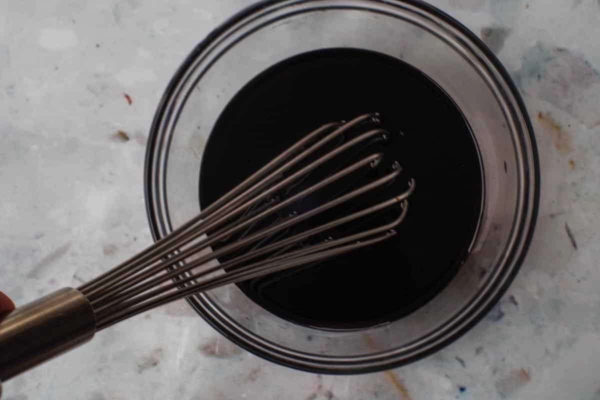 Sauce ingredients mixed together in glass bowl with spoon,