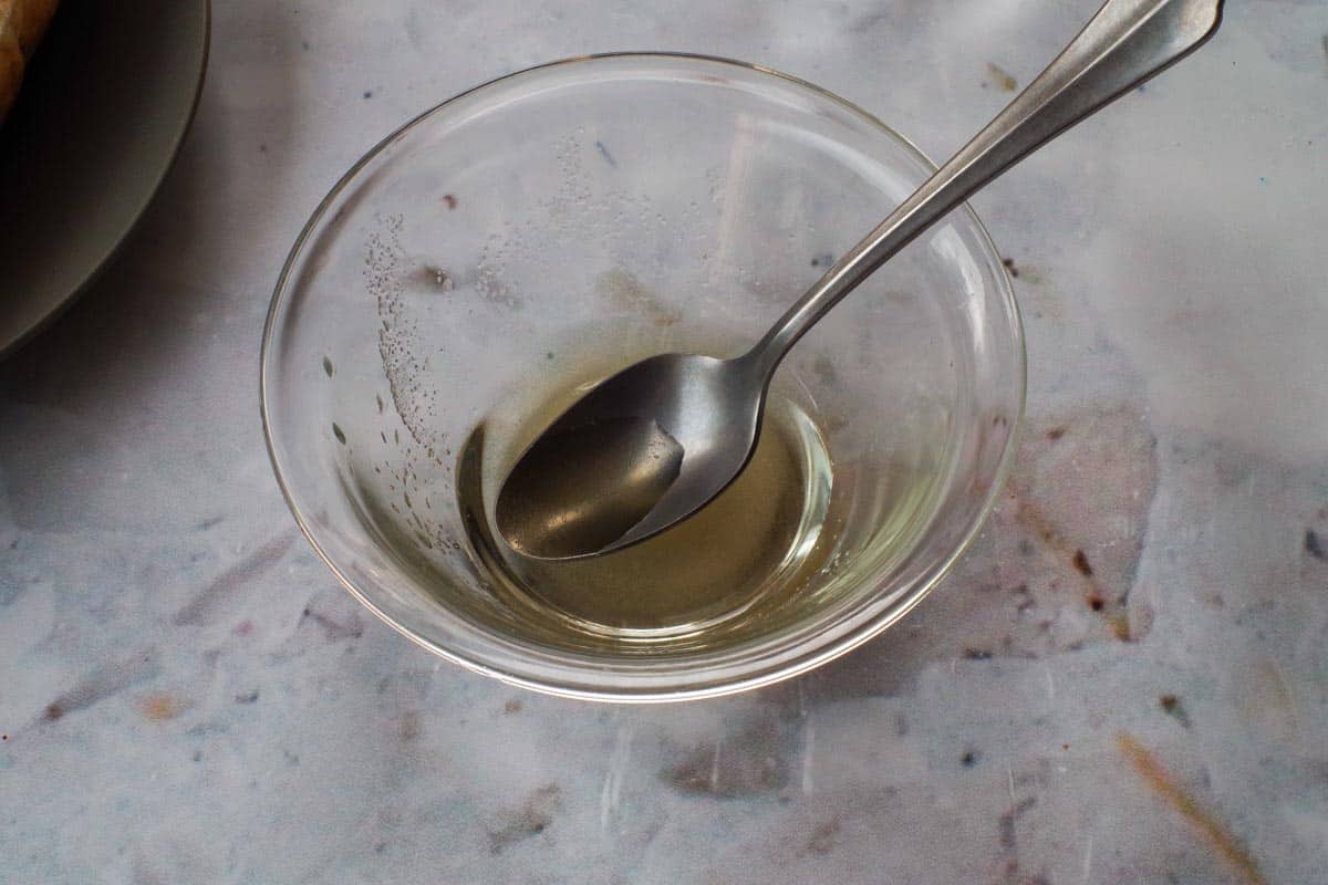 Sugar and rice vinegar mixed together in a small glass with a spoon.