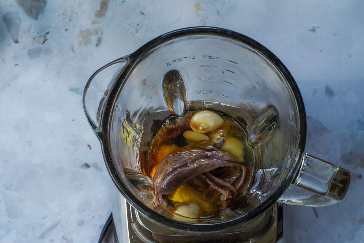 Caesar salad dressing ingredients in the bowl of a blender.