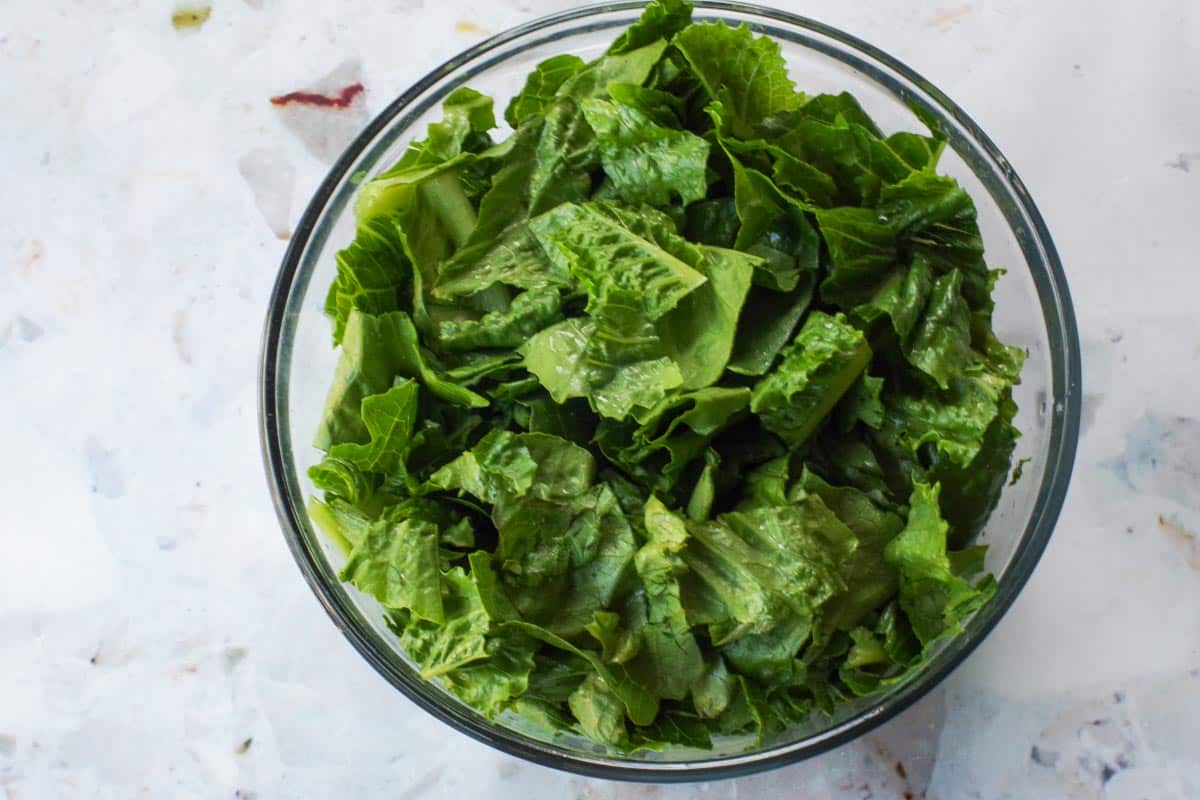 Lettuce cut into bite-sized pieces in glass bowl.
