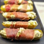 6 Boursin stuffed pickles on a black serving platter.