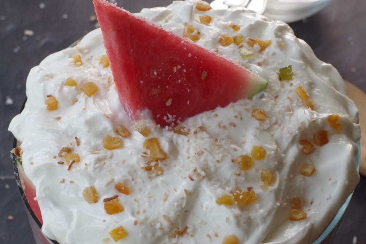 Watermelon trifle finished with yogurt on top and garnished with candied citrus peel and a slice of watermelon.