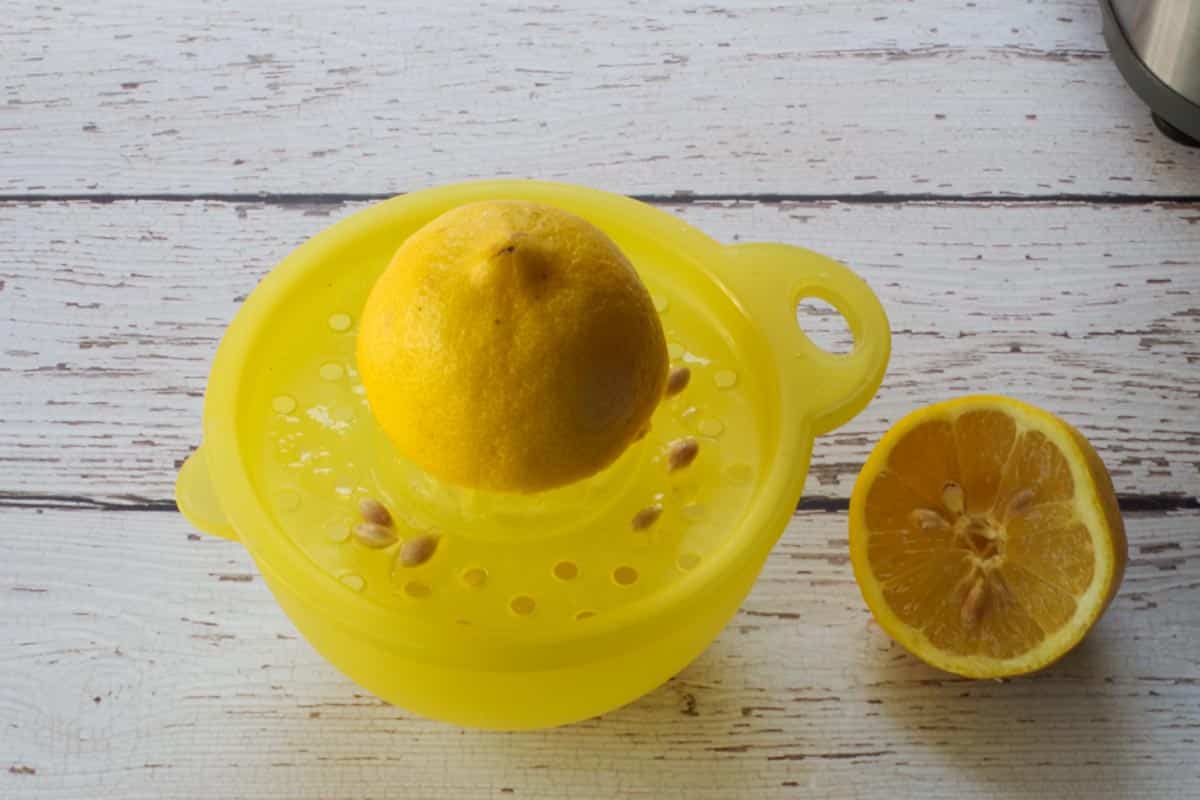 Lemon being juiced with a manual juicer.