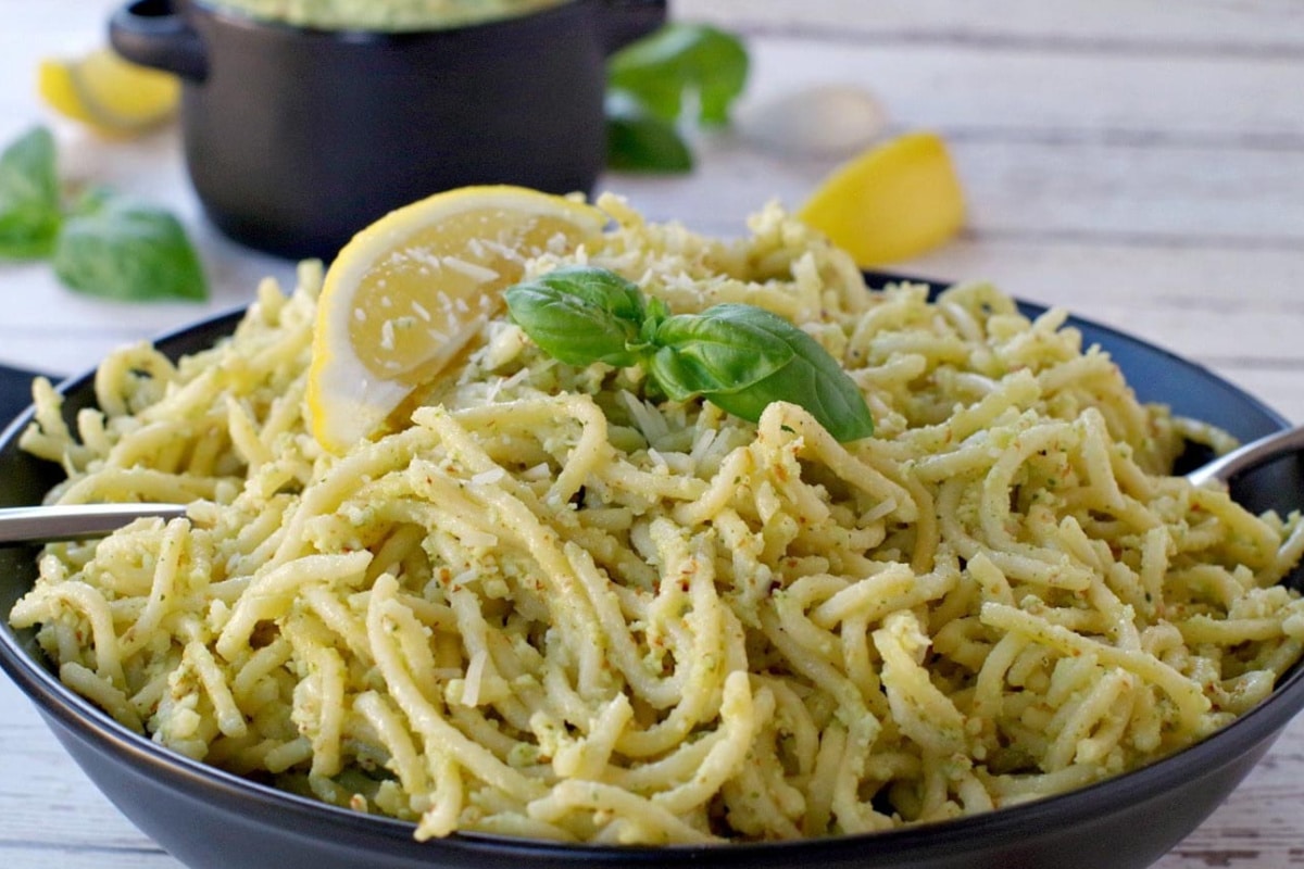 pesto on spaghetti noodles with more pesto (in black container in background)