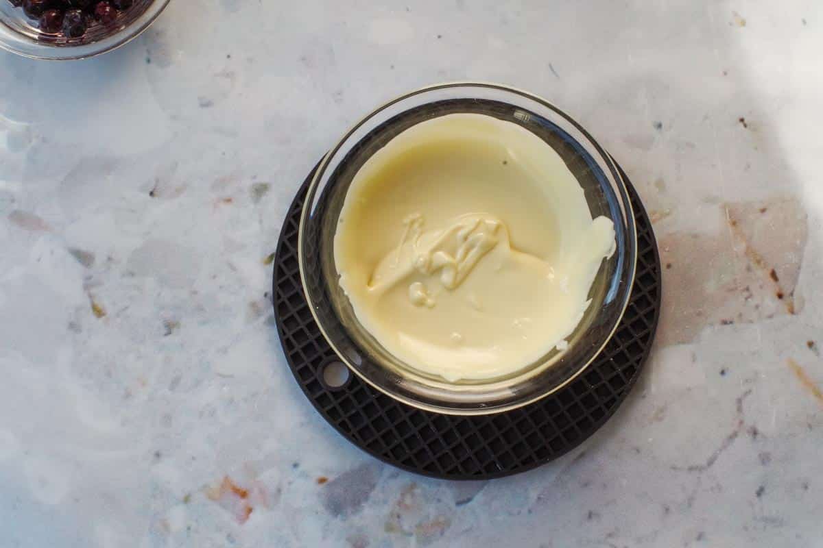 Melted white chocolate in a small glass bowl.