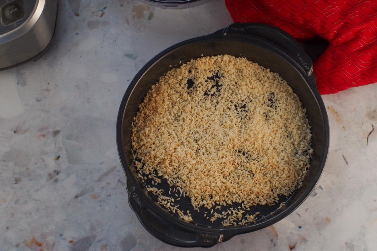 Toasted coconut in a round baking pan.