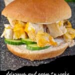 Chicken breat burger on a cutting board with sliced cucumbers in the background.