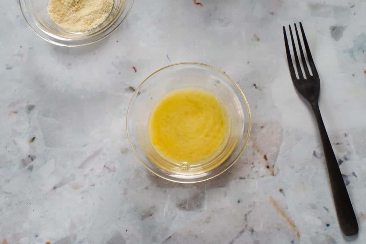 Egg wash in a small glass bowl, with a fork beisde it.