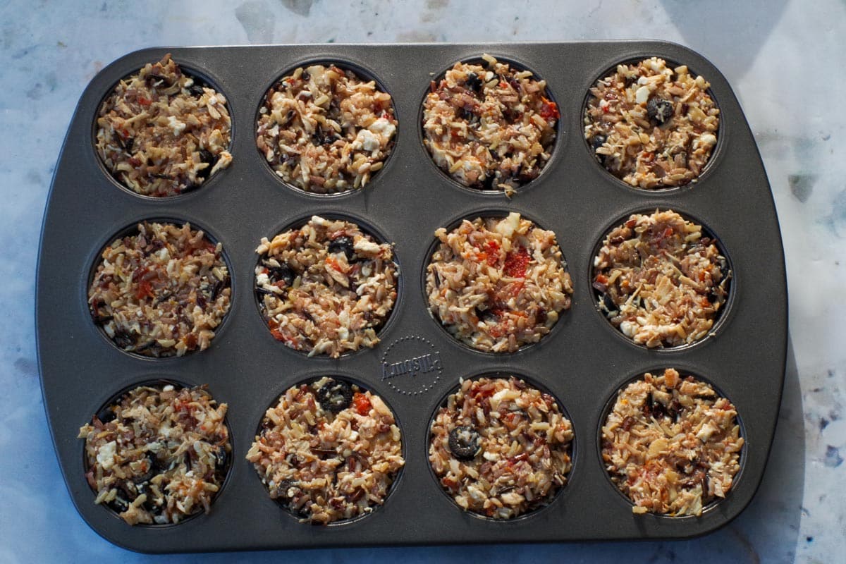 Rice mixture pressed tightly into prepared muffin tins.