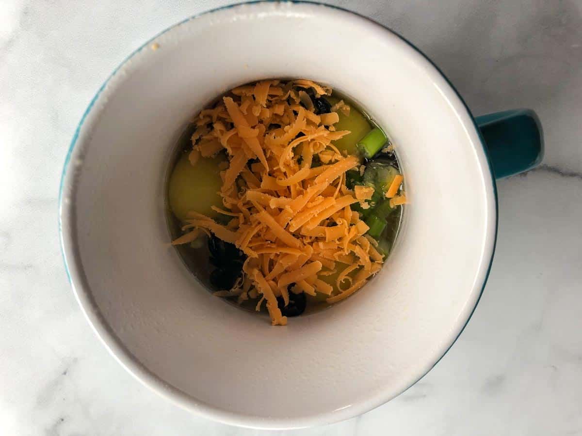 Fillings added to eggs in microwave-safe mug.