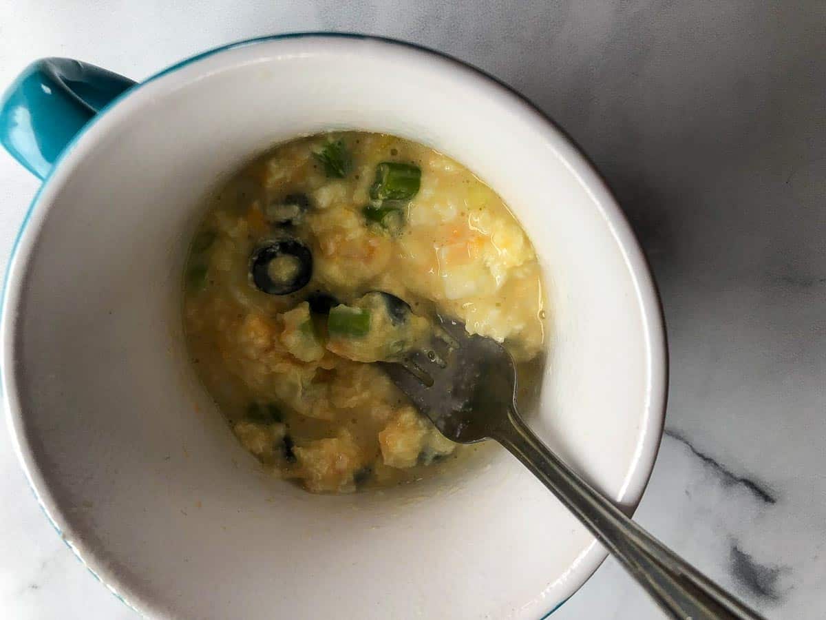 Omelette being beaten with a fork after it's been cooked a short time.