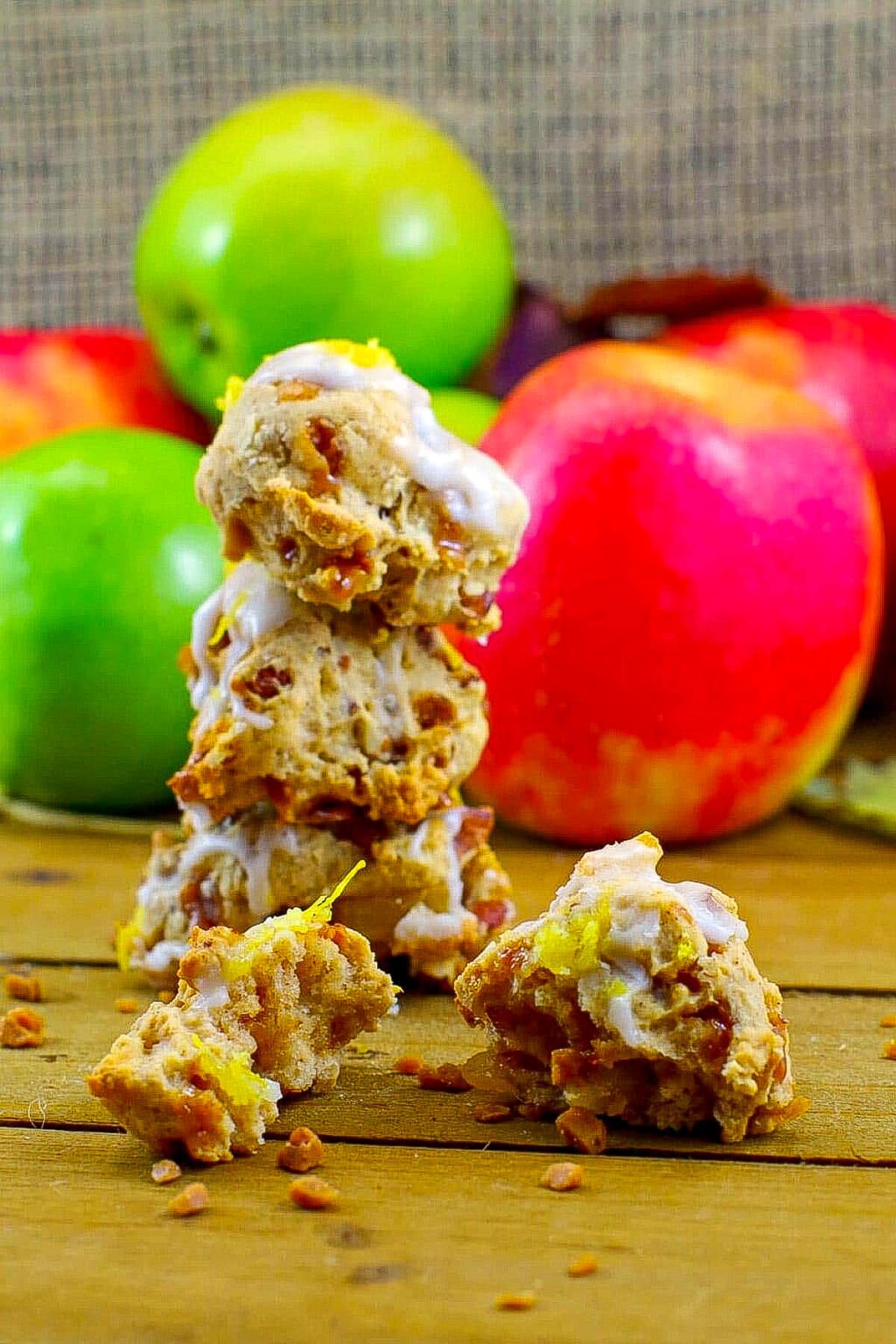 3 toffee apple cookies stacked and a split cookie in front with apples in the background.